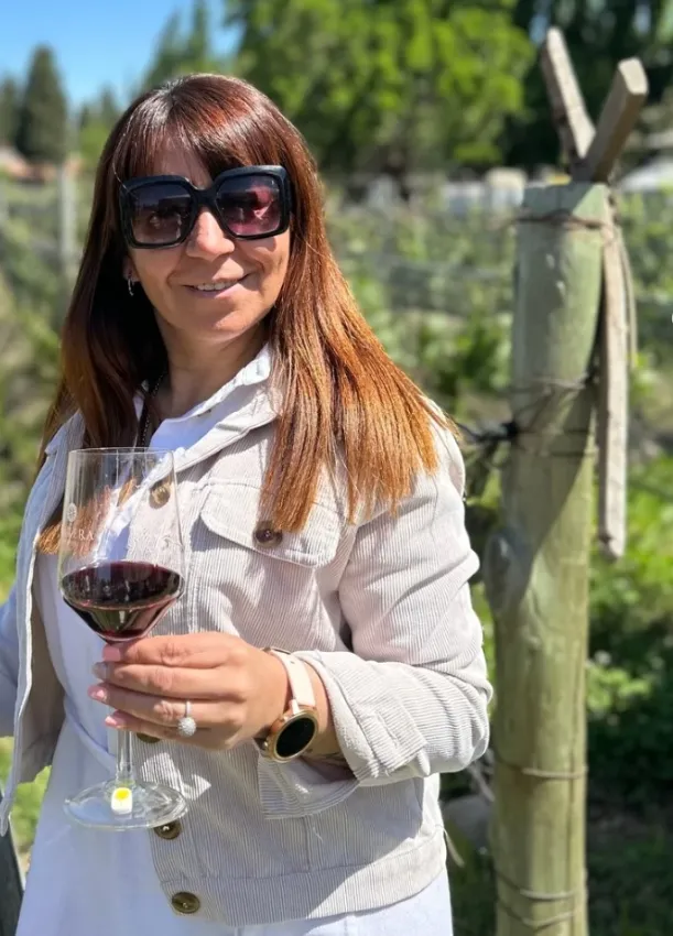 Mujer con una copa de vino tinto en un viñedo